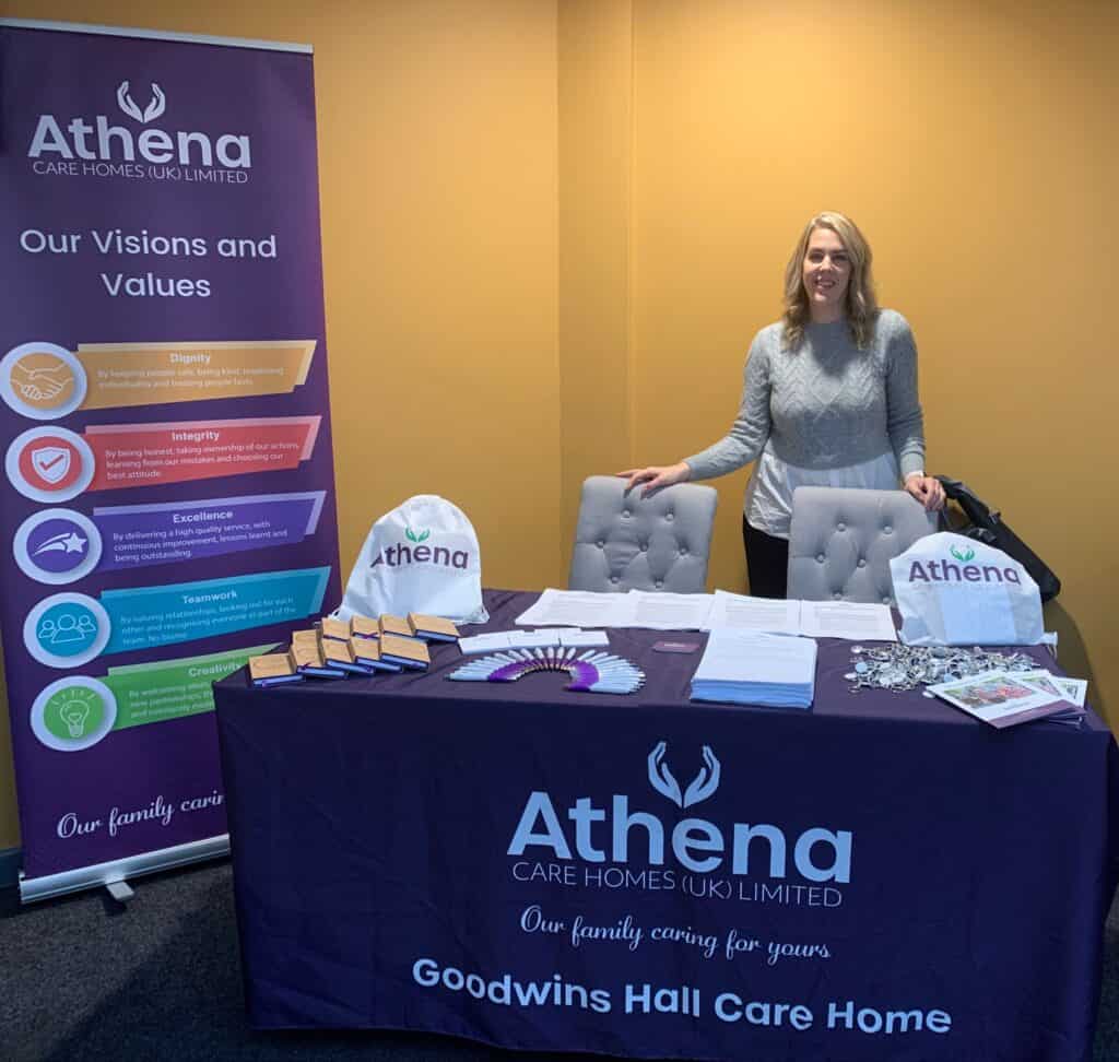 Woman stood at Athena Care Homes branded table at college career event