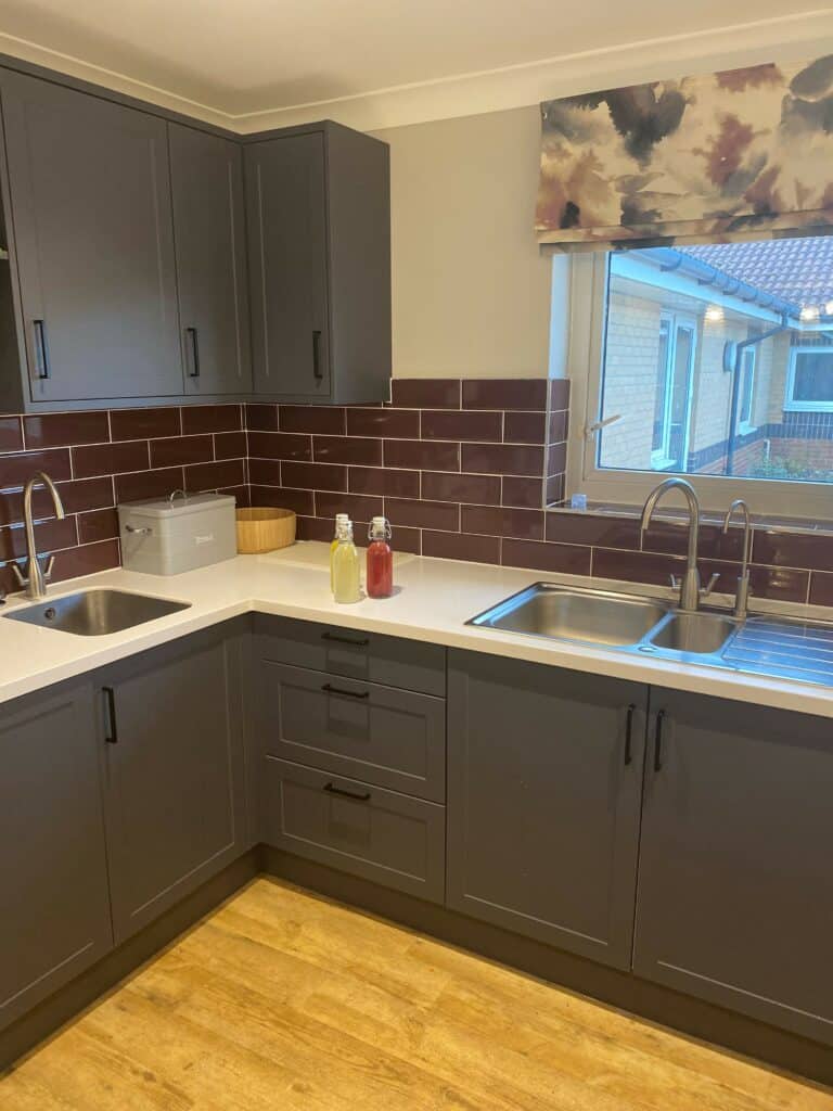 Grey kitchen units with maroon tiles in care home