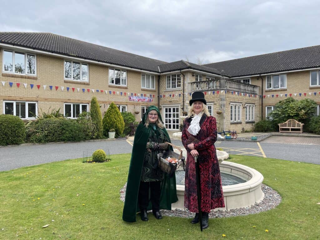 Two women in period costume stand outside care home