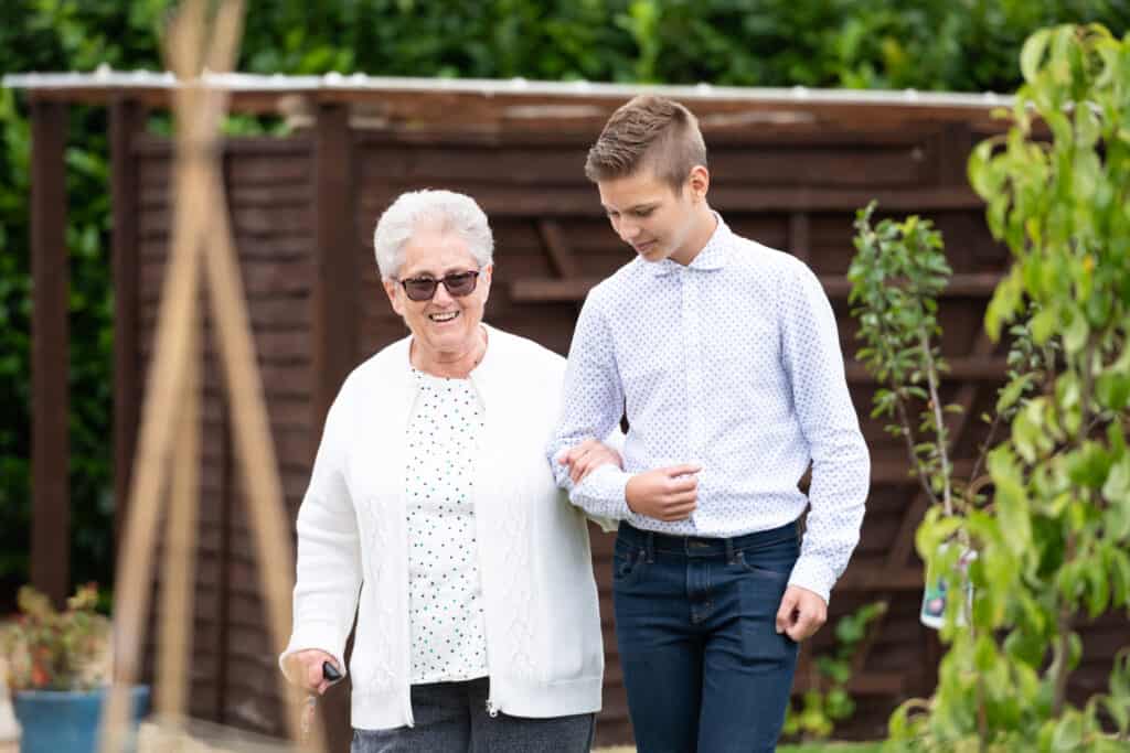 Older woman and grandson walk in garden at care home